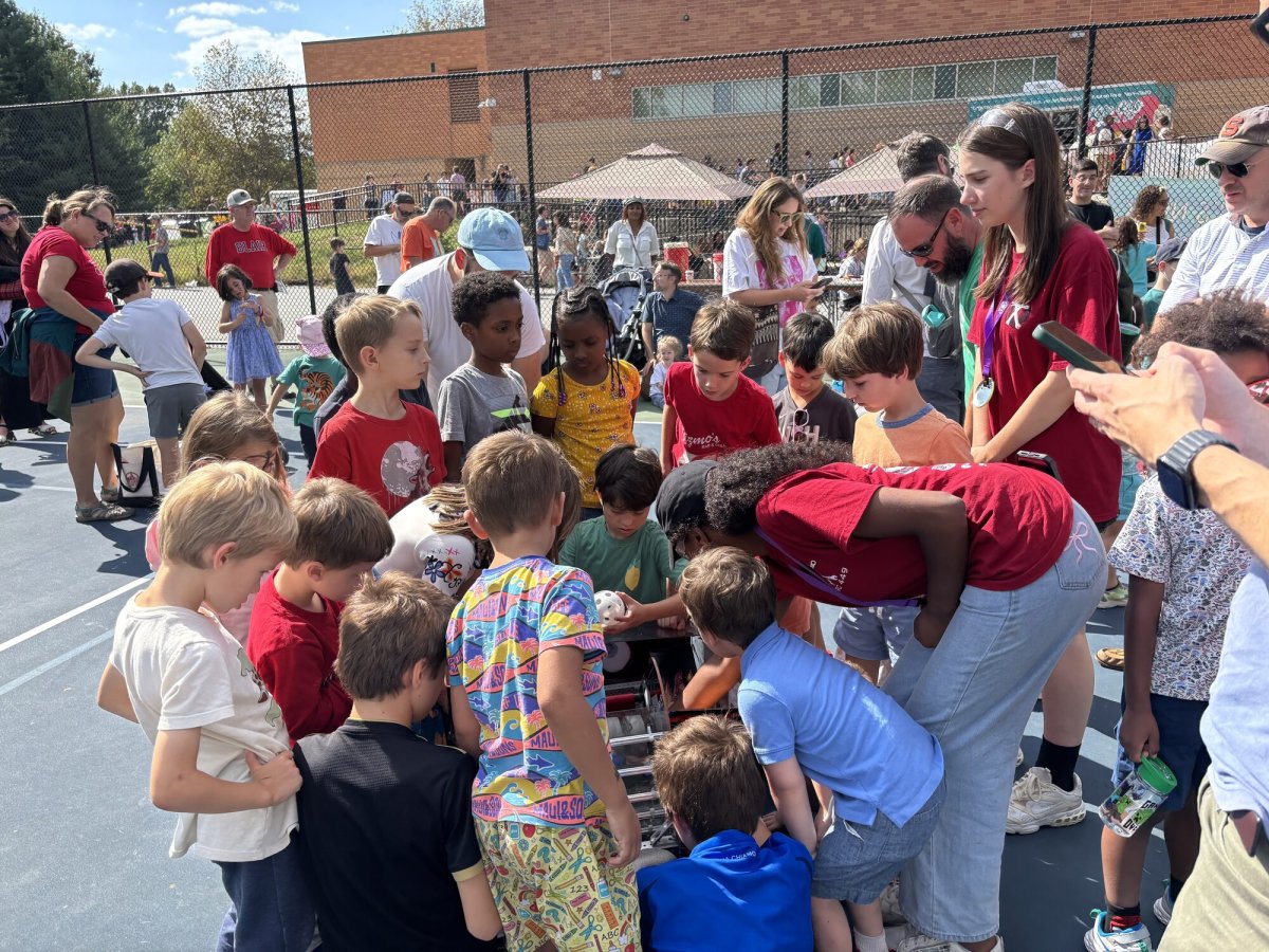 Team member showing young children a demo robot at a community outreach event